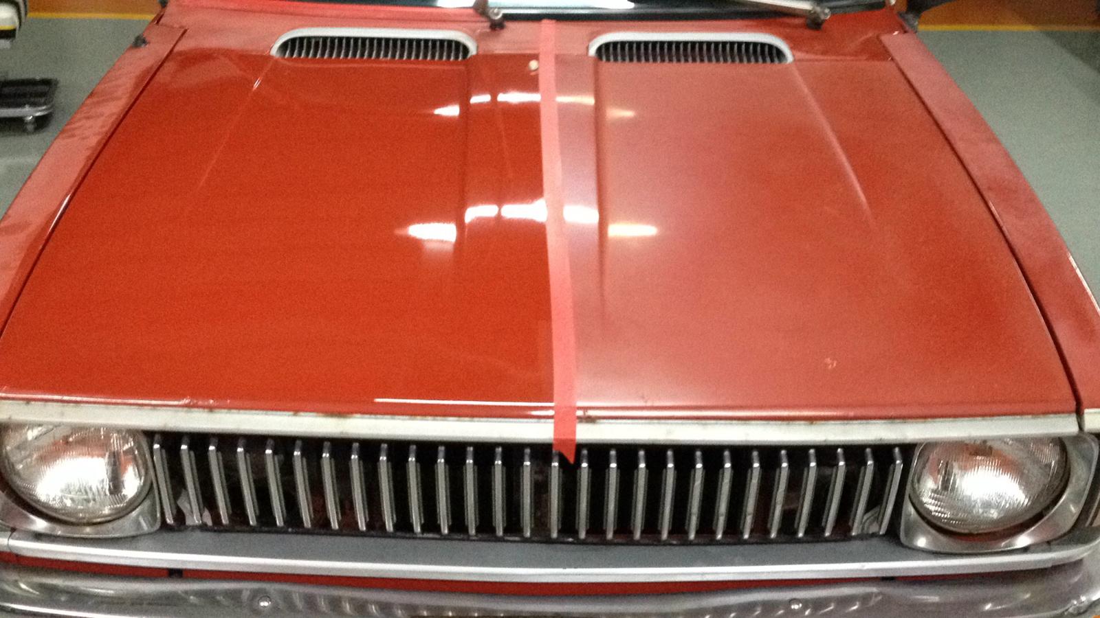 Red 1974 Toyota Corolla hood showing before and after paint correction